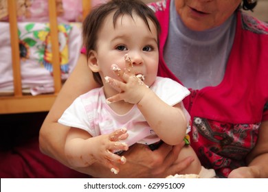 Portrait Of Grandmother With Her Grandchild Eating A Slice Of Birthday Smash Cake