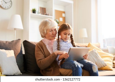 Portrait of grandmother reading stories to cute little girl using digital tablet together, copy space - Shutterstock ID 1362127772