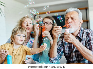 Portrait of grandparents and grandchildren having fun  blowing soap  bubbles together at home - Powered by Shutterstock