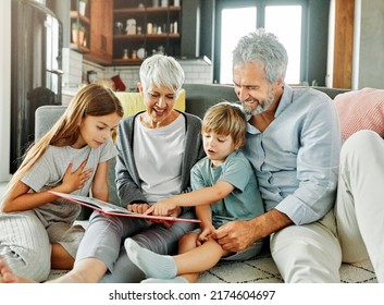 Portrait of grandparents and grandchildren having fun together reading a book at home - Powered by Shutterstock