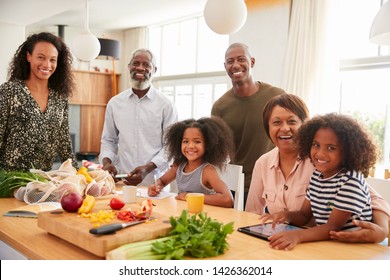 Portrait Of Grandparents Sitting At Table With Grandchildren Playing Games As Family Prepares Meal - Powered by Shutterstock