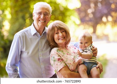 Portrait Of Grandparents Walking In Outdoors With Baby Grandson