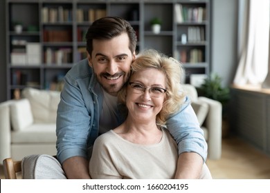 Portrait of grateful adult man hug smiling middle-aged mother show love and care, thankful happy grown-up son in embrace senior 70s mom, enjoy weekend family time at home together, bonding concept