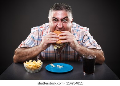 Portrait Of A Greedy Fat Man Eating Burger On Gray Background