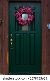 Portrait Of A Green Front Door With A Summer Wreath Hanging On It 