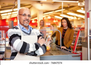 Portrait Of A Grocery Store Cashier Standing At A Checkout Counter