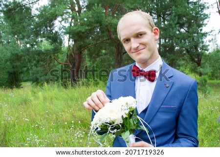 Portrait of the groom of European appearance in a blue wedding suit with a bouquet of flowers.
