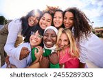 Portrait of group of beautiful young multiracial girl friends community hugging and looking at camera outdoor. Smiling only women together embraced affectionately. Female friendships and quality time