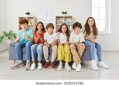 Portrait of a group of children, kids sits on a sofa at home, watching a sports match on television together. Schoolchildren excitement and camaraderie as they enjoy the TV game as friends. - Powered by Shutterstock