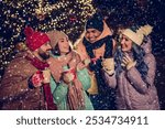 Portrait of group four buddies hold hot chocolate mug speak communicate enjoy festive atmosphere tree garland town center outdoors