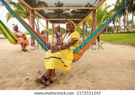 Portrait of a group of Garifuna women sitting in hammocks wearing beautiful dresses typical of Livingston Izabal.
