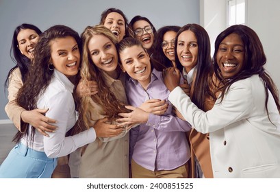 Portrait of group of happy cheerfull young diverse women friends coworkers and company employees hugging looking at camera posing and smiling on grey background. Diversity, friendship concept. - Powered by Shutterstock