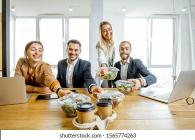 Portrait of a group of office workers taking business lunches in the office. Concept of healthy takeaway food on the work - Powered by Shutterstock