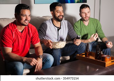 Portrait Of A Group Of Three Guys Hanging Out And Watching TV At Night With Beer And Some Popcorn