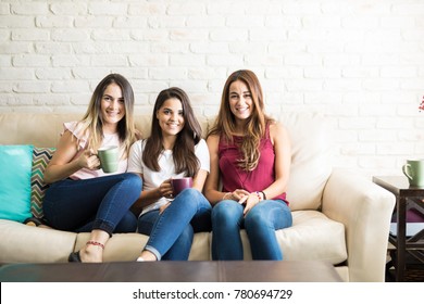 Portrait Of A Group Of Three Roomates Enjoying A Cup Of Coffee At Home And Smiling