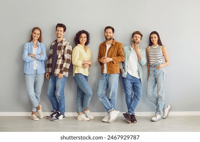 Portrait of a group of young happy smiling friends students or colleagues in casual clothes standing together posing isolated on a gray background and looking confidently and positively at camera. - Powered by Shutterstock