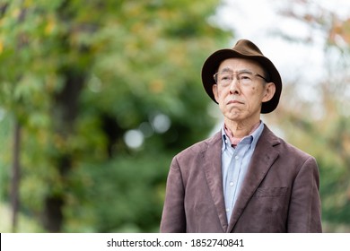 Portrait Of Grumpy Senior Asian Man Wearing Jacket In Park