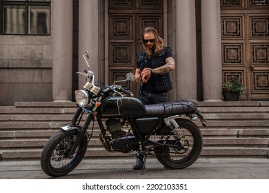 Portrait Of Guy Dressed Like Rocker Looking At His Watch Driving Bike.