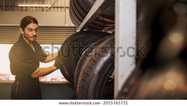 Portrait guy mechanic in the car service center\
chooses new tires that are quality and suitable for driving on the\
road for the benefit and safety of the customers : Male mechanics\
in the auto service