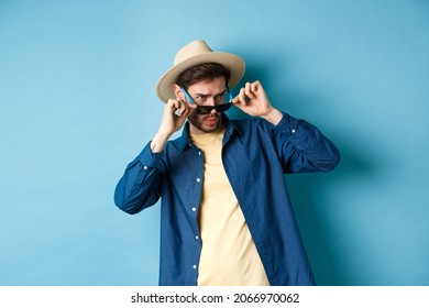 Portrait Of Guy On Vacation Staring Aside With Shocked And Cringe Face, Take-off Sunglasses And Look At Empty Space On Blue Background