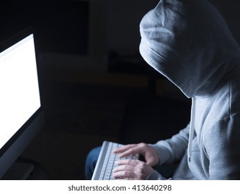 Portrait of hacker in the sitting in front of computer with glow
