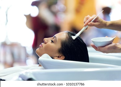 Portrait of the hairdresser applying hair treatment for customer in a beauty salon. 