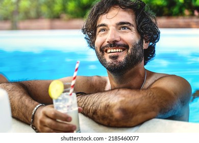 Portrait of a hairy man relaxing by drinking a refreshing cocktail and chatting with friends while taking a bath in the pool - concept of summer vacation and carefree life outdoors