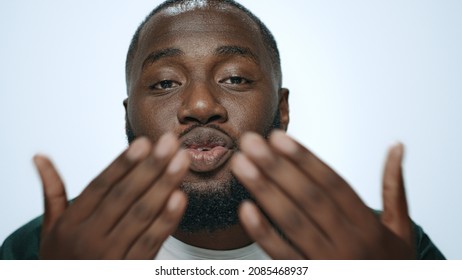 Portrait Handsome African American Man Sending Air Kiss To Camera. Smiling Guy Flirting Camera On White Background. Closeup Playful Person Blowing Air Kiss From Hand In Slow Motion. Pickup Concept