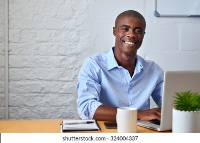 Porträt eines gut aussehenden schwarzen Geschäftsmanns, der am Schreibtisch auf Laptop-Computern arbeitet
