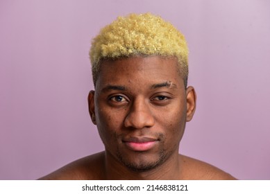 Portrait of a handsome African man with short blond hair on a pastel pink background in a studio