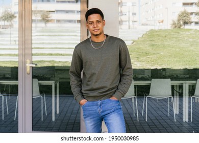 Portrait Of A Handsome Afro Boy Looking At The Camera Leaning Against The Wall. Latino Man In His 20's With His Hands In His Jeans Pocket. Space For Copy Space