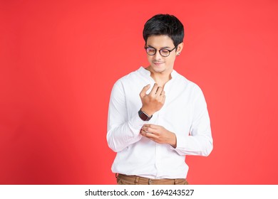 portrait handsome asian businessman adjusting his tshirt sleeve facial hair smiling looking straight wearing glasses and casual clothing and black earrings, standing and posing red isolated background - Powered by Shutterstock