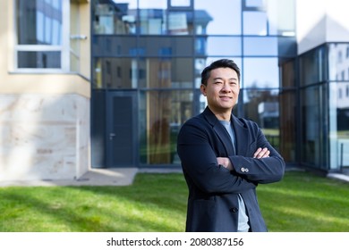 Portrait Handsome Asian Man A University College Teacher, Businessman, Scientist Or Educator. Standing Background Modern Office Center Or Campus With Arms Crossed Outside, Outdoors Looking At Camera