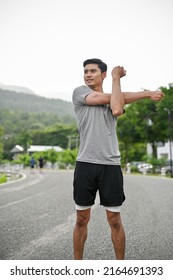 Portrait of a handsome asian young in active and comfy sportswear stretching his arms and body before running, training or jogging. - Shutterstock ID 2164691393