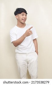 Portrait Of Handsome Asian Young Man Smiling While Pointing Sideways In Empty Space