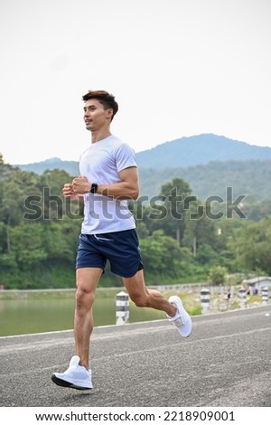 Portrait, Handsome athletic fit young Asian man in sportswear concentrating on running outdoors in the morning.