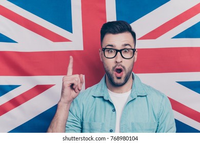 Portrait of handsome attractive guy with stubble in glasses showing index finger up, find a solution, have an idea with opened mouth over English flag background - Shutterstock ID 768980104