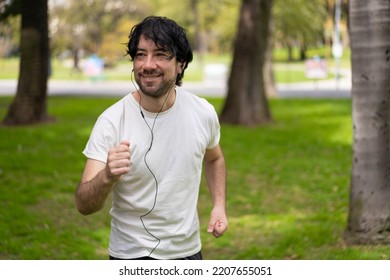 Portrait Of Handsome Attractive Mature Bearded Athletic Latin Man Guy 40s In Casual White T-shirt Running At A Park