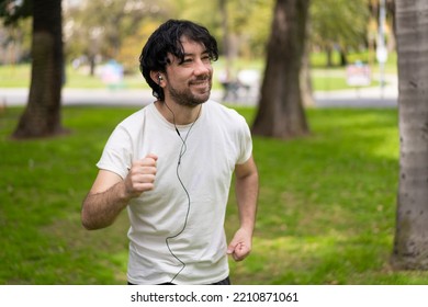 Portrait Of Handsome Attractive Mature Bearded Athletic Latin Man Guy 40s In Casual White T-shirt Running At A Park, Looking Aside