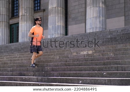 Portrait of handsome attractive mature bearded athletic latin man guy 40s in orange t-shirt running on some stairs
