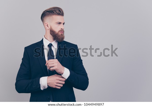 グレイの背景に横向きの袖に袖口のカフスを固定する男性の上司で 美しくて上品で自信たっぷりの豪華な男性のポートレート の写真素材 今すぐ編集
