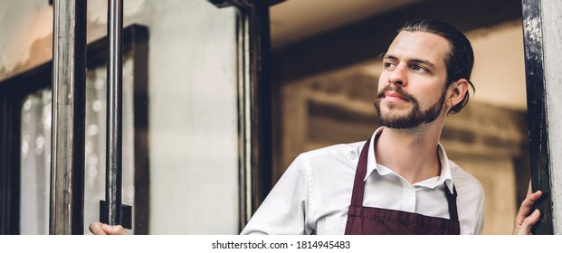 Portrait of handsome bearded barista man small business owner smiling outside the cafe or coffee shop.Male barista standing at cafe - Shutterstock ID 1814945483