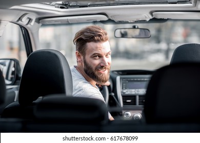 Portrait Of A Handsome Bearded Man Looking Back Sitting On The Front Seat Of The Car