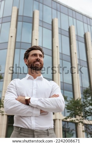Portrait of handsome bearded man on city street, low angle view. Space for text