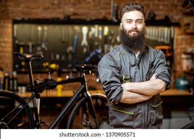 Portrait of a handsome bearded repairman in workwear at the bicycle workshop