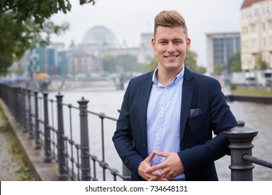 portrait of handsome blond man with german parliament in the background