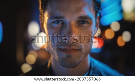 Portrait of Handsome Blonde Man Smiling and Looking at Camera, Standing in Night City with Bokeh Neon Street Lights in Background. Confident Young Man with Stylish Hair. Close-up Portrait.
