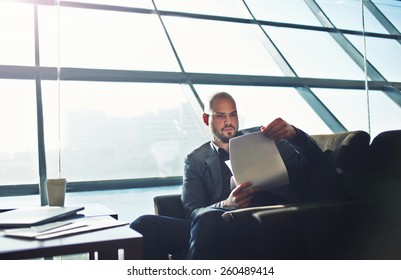Portrait of handsome businessman examining paperwork in office interior, male executive studies documents or papers during his coffee time - Shutterstock ID 260489414