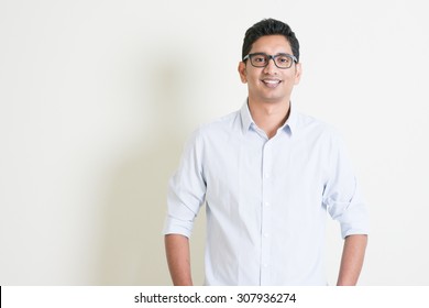 Portrait Of Handsome Casual Business Indian Man Smiling And Looking At Camera, Standing On Plain Background With Shadow, Copy Space At Side.