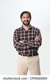 Portrait Of Handsome Casual Indian  Business Man Smiling, Folded Hands Standing On Plain Background